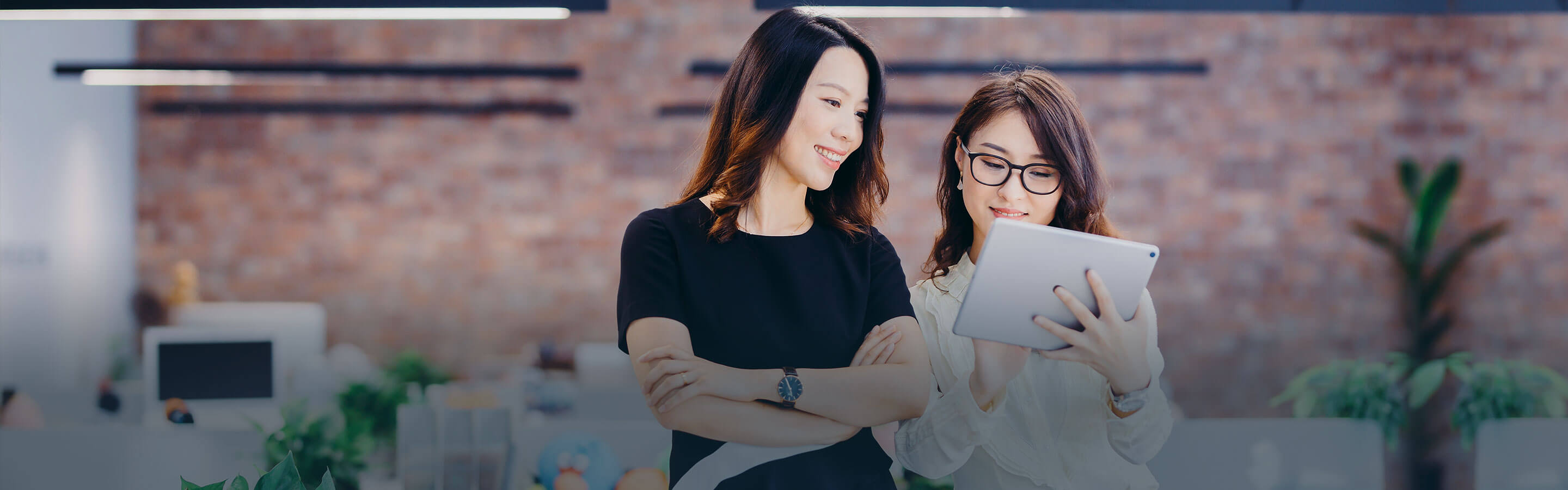 Two women in an office interacting with a tablet