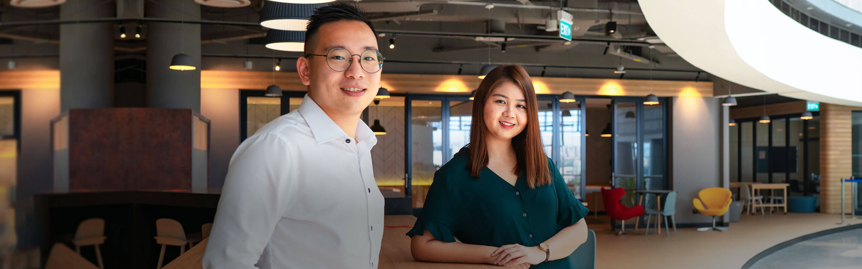 Two employees posing against a table in an office