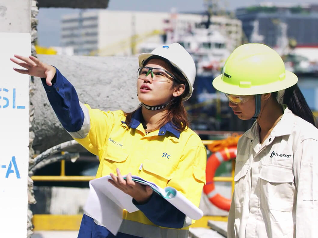 Two employees in hard hats doing outdoor inspections at a site