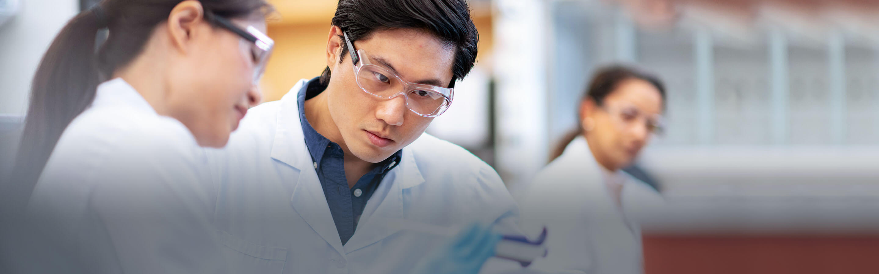 Researchers in lab coats and safety goggles conducting R&D