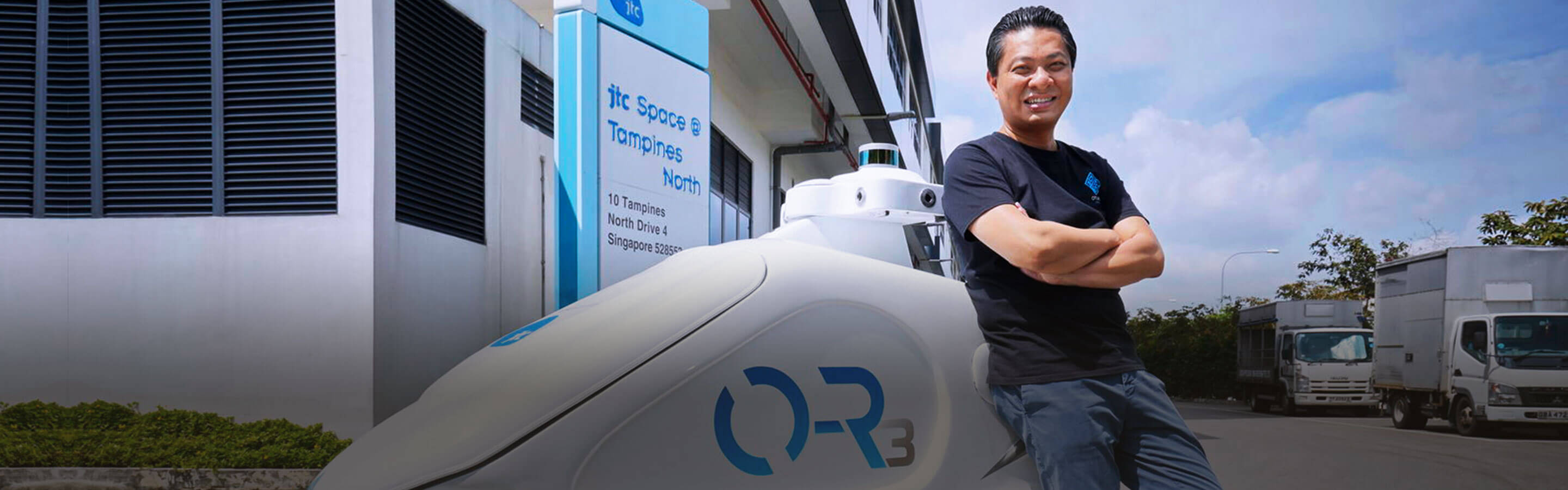 Man from robotics posing with an autonomous robot in an industrial estate