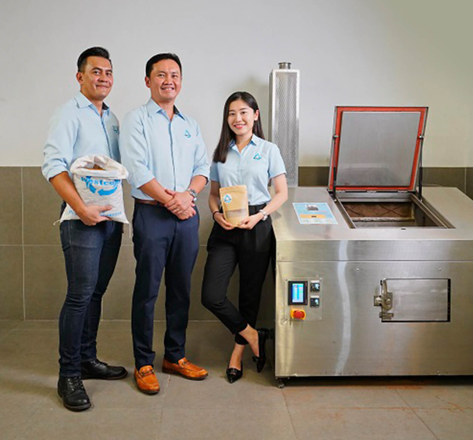 Three employees posing next to a machine in a smart factory