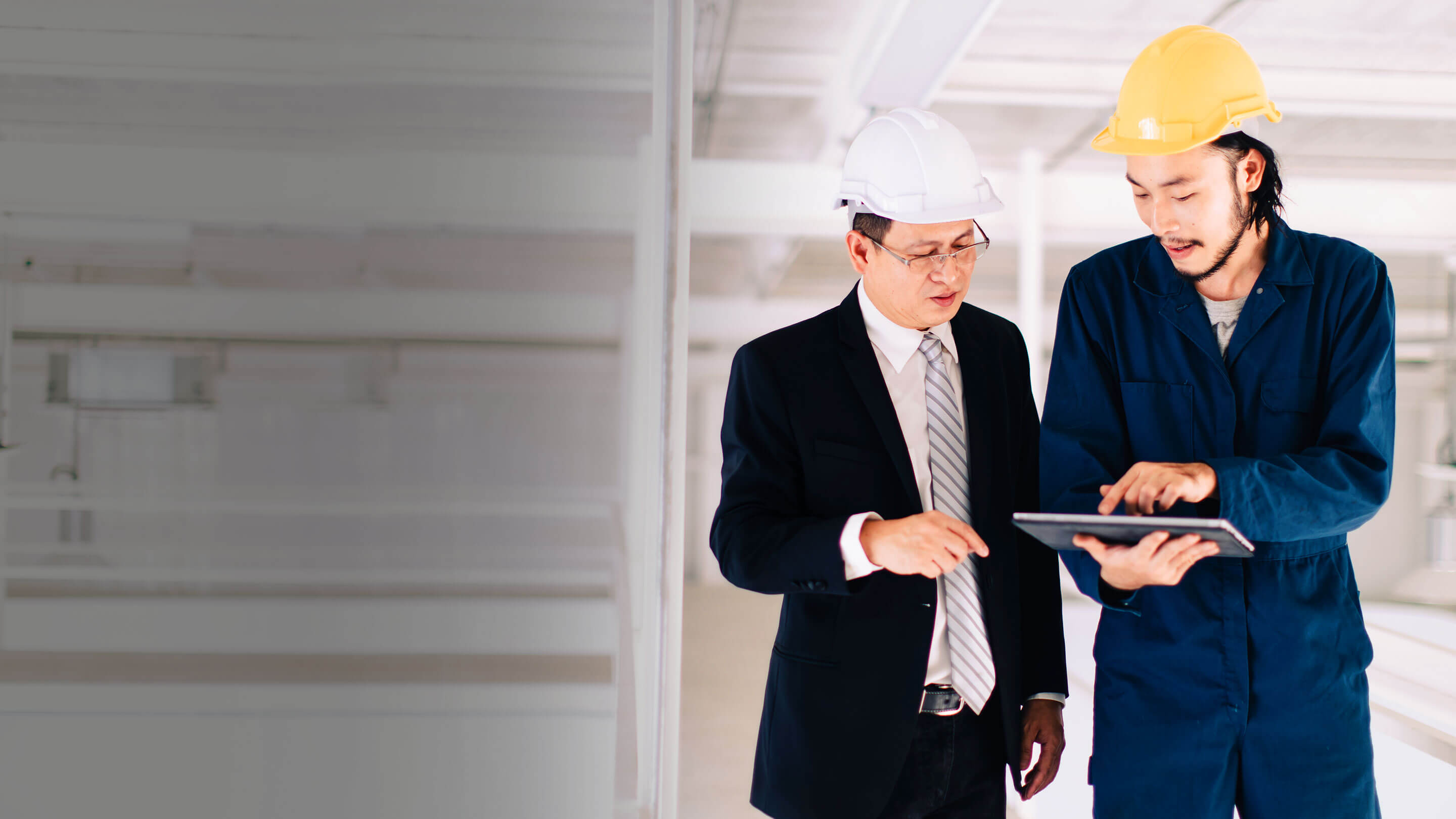 A worker and businessman in safety helmets having a discussion in a facility