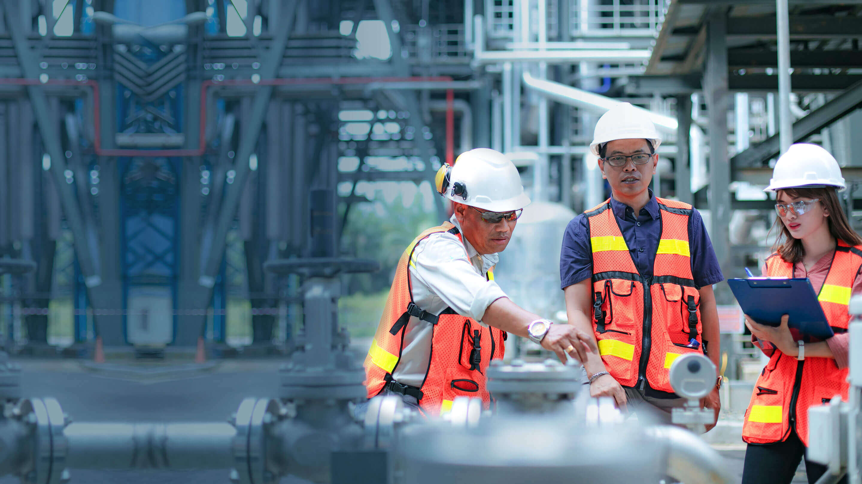 Employees in safety helmets, vests and goggles conducting outdoor checks at a facility