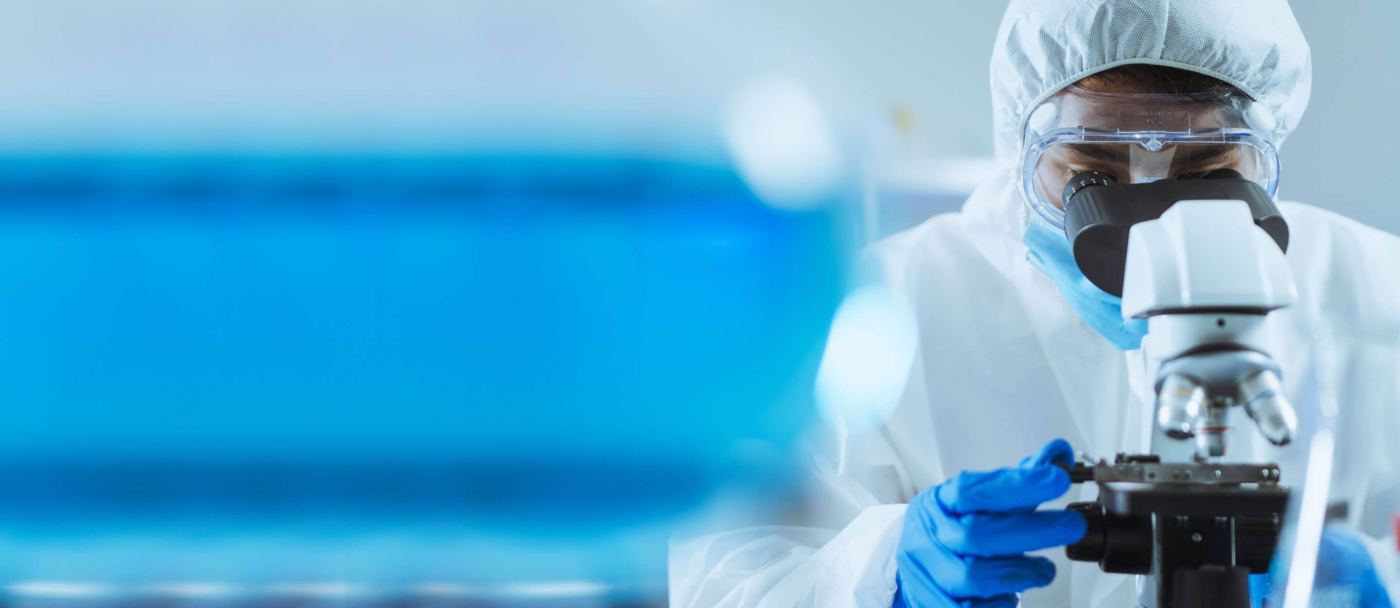 A scientist examines specimens under a microscope