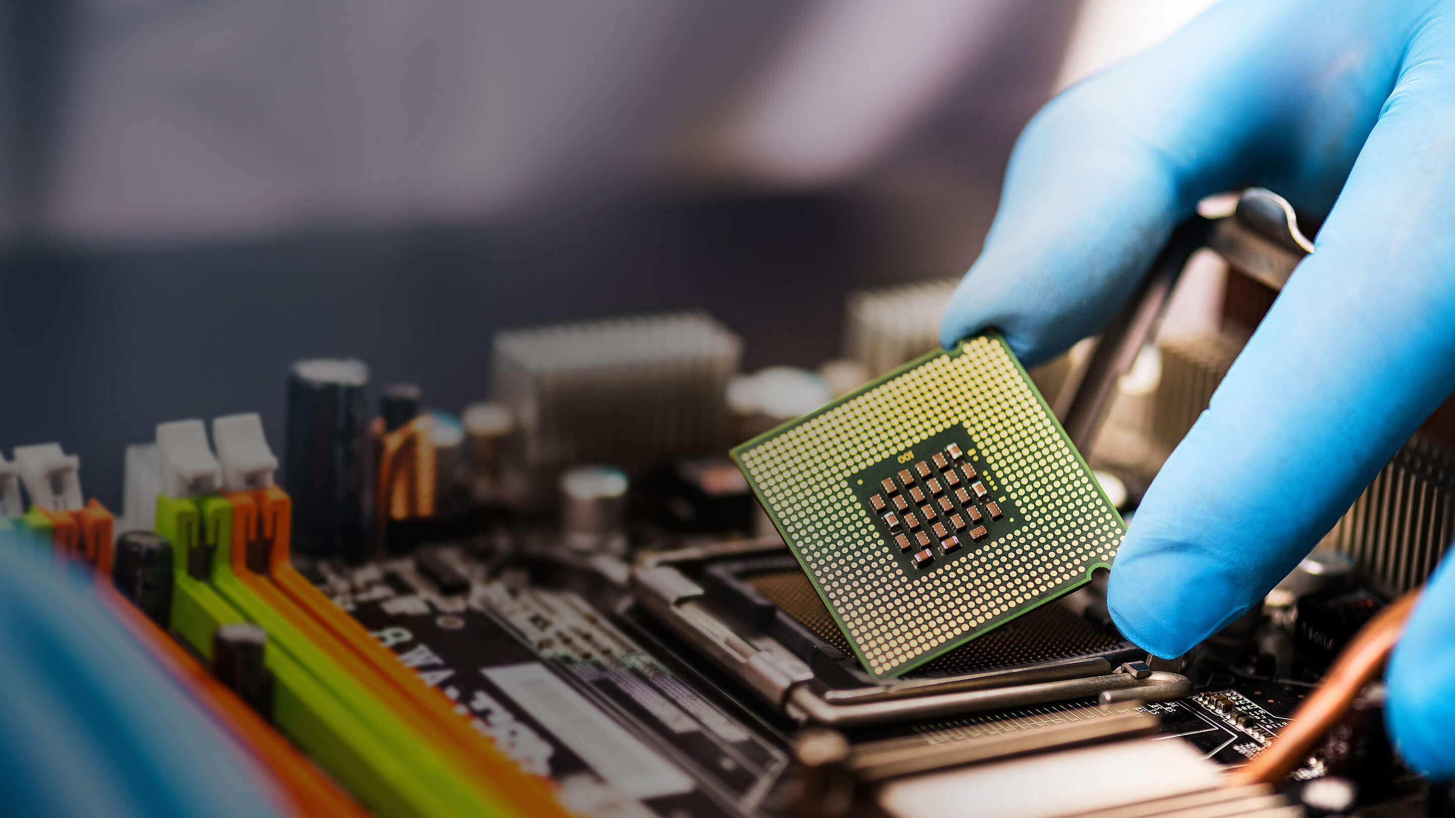 Close-up of a hand lifting a microchip from a circuit board