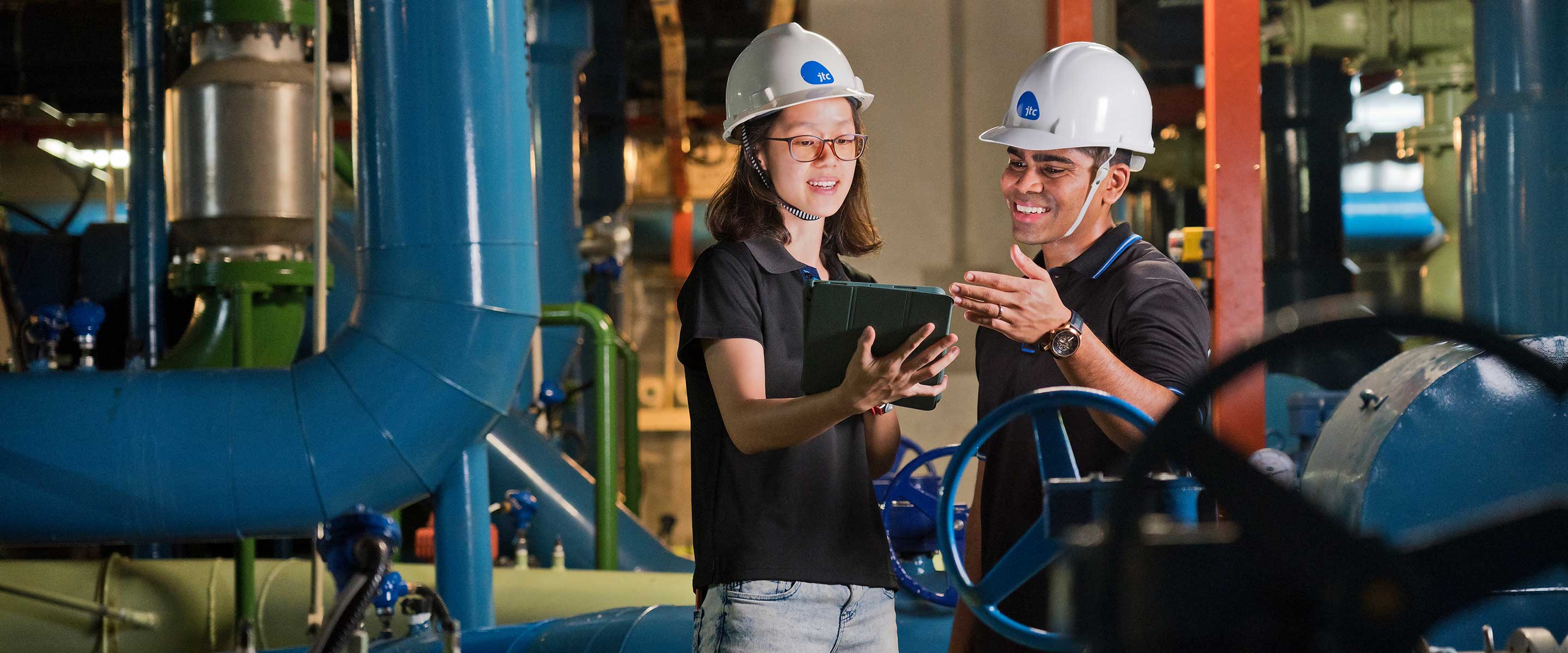 Two workers in hard hats conducting checks in an indoor facility