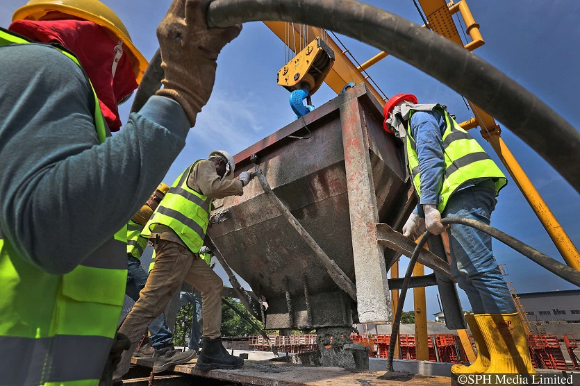 Concrete being discharged from a bucket into the mould of a bridge segment, as workers use a vibrating rod to make sure the concrete is well mixed, at the Coninco precast yard.