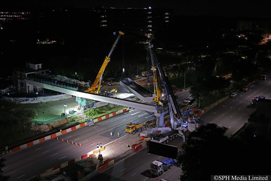   A bridge segment being transferred from one crane to another, while hoisted in the air, in Jurong West 